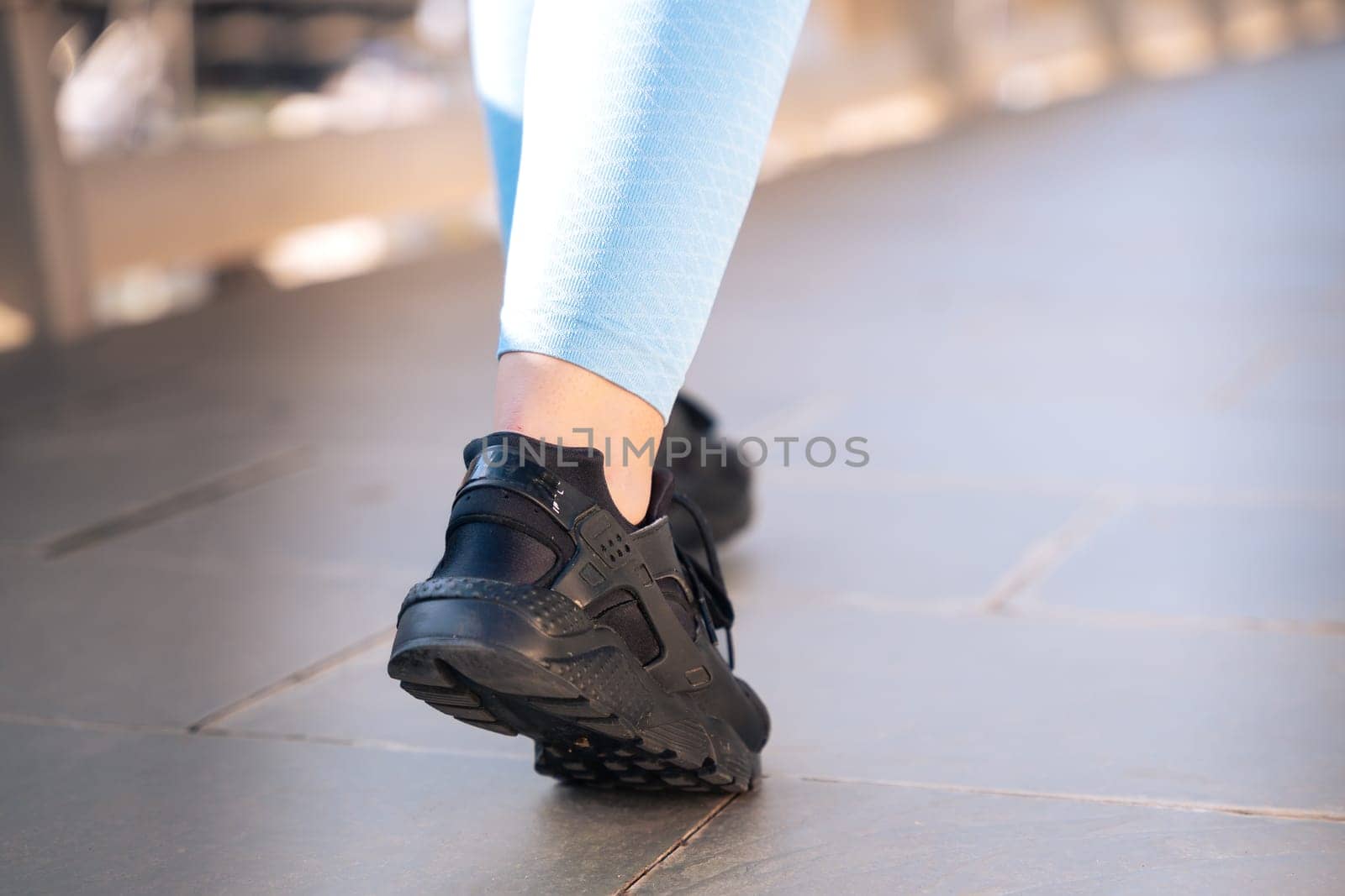 Feet of a sporty woman running through the streets of the city.