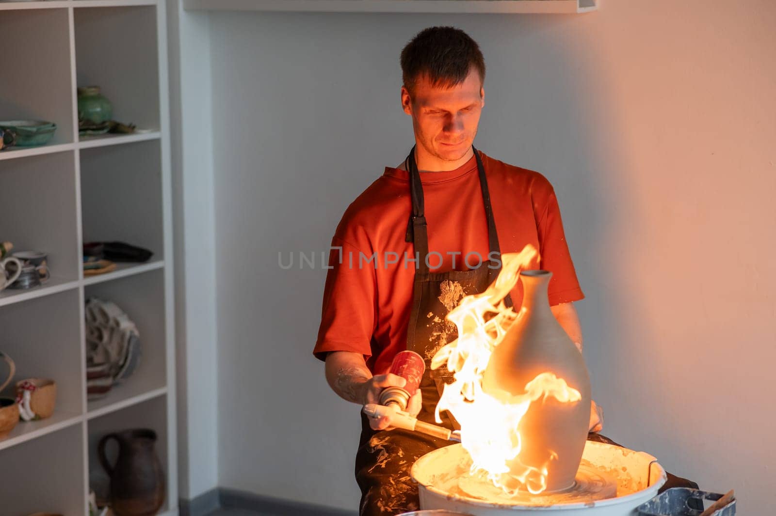 A potter burns a jug with a gas burner on a potter's wheel. by mrwed54