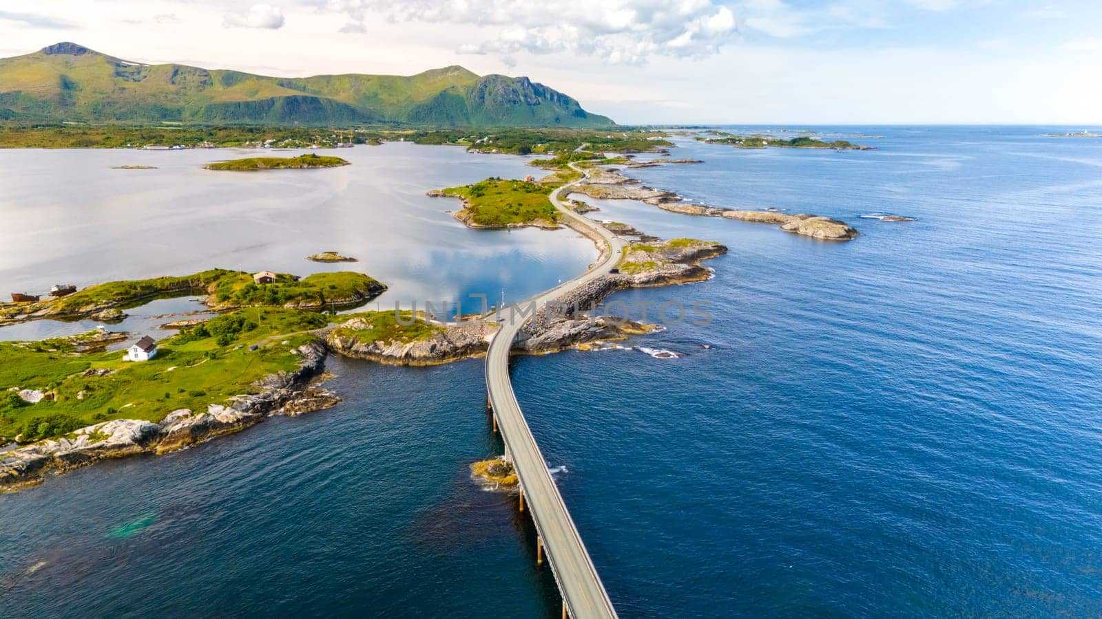 Aerial view of winding road over turquoise waters along Norways coastline, connecting small islands in a picturesque route through a stunning landscape. Atlantic Ocean Road Norway