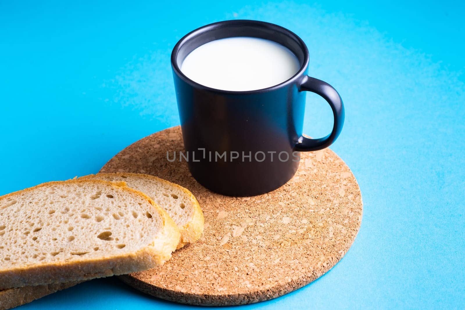 Breakfast bread and a cup of milk on yellow and blue background by Zelenin