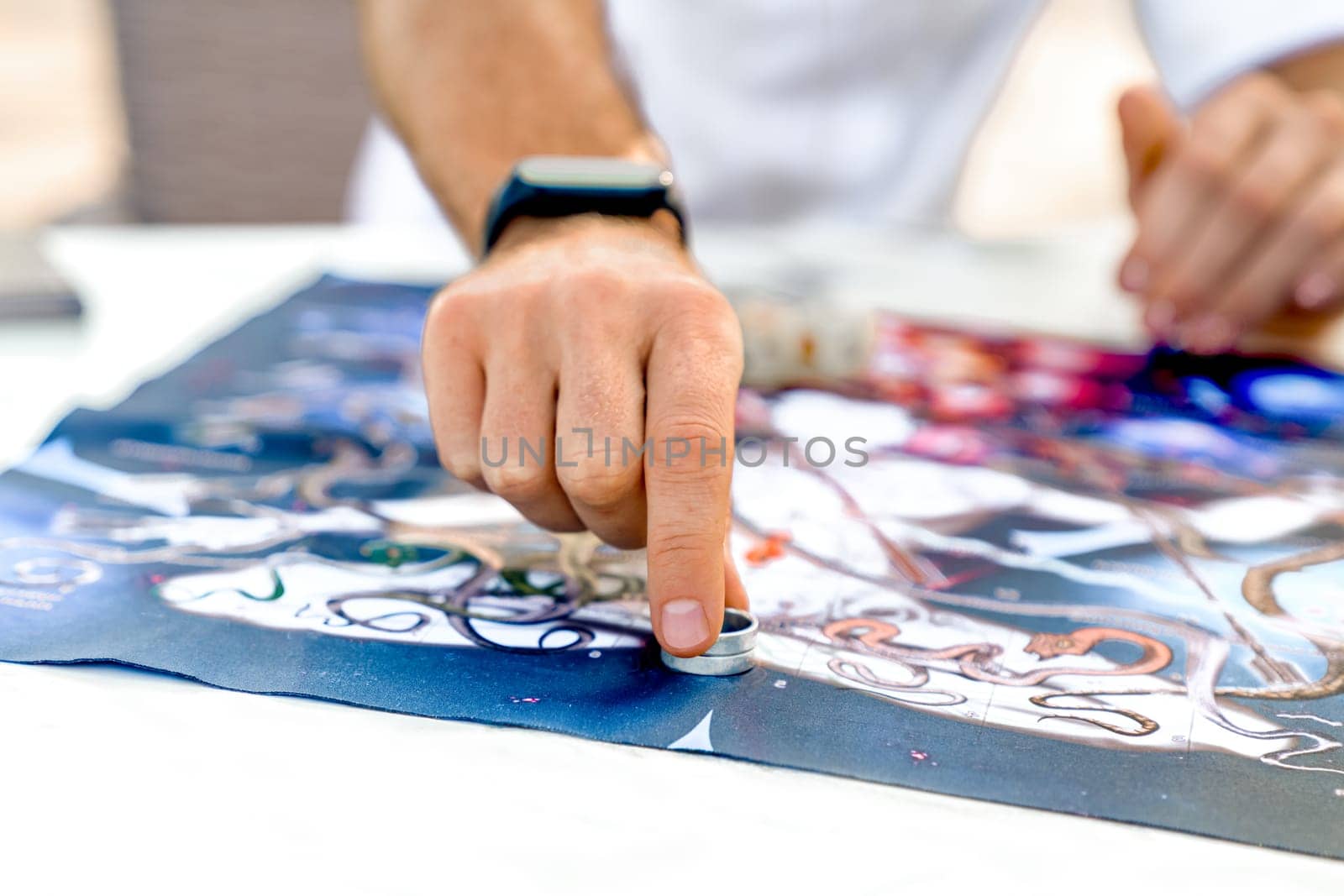 Man Makes Move with Game Chip in Form of Ring After Rolling Dice, Close-Up of Hands on Background with Game Board, Ancient Indian Game Leela, Turkey, Alanya - April 14, 2024