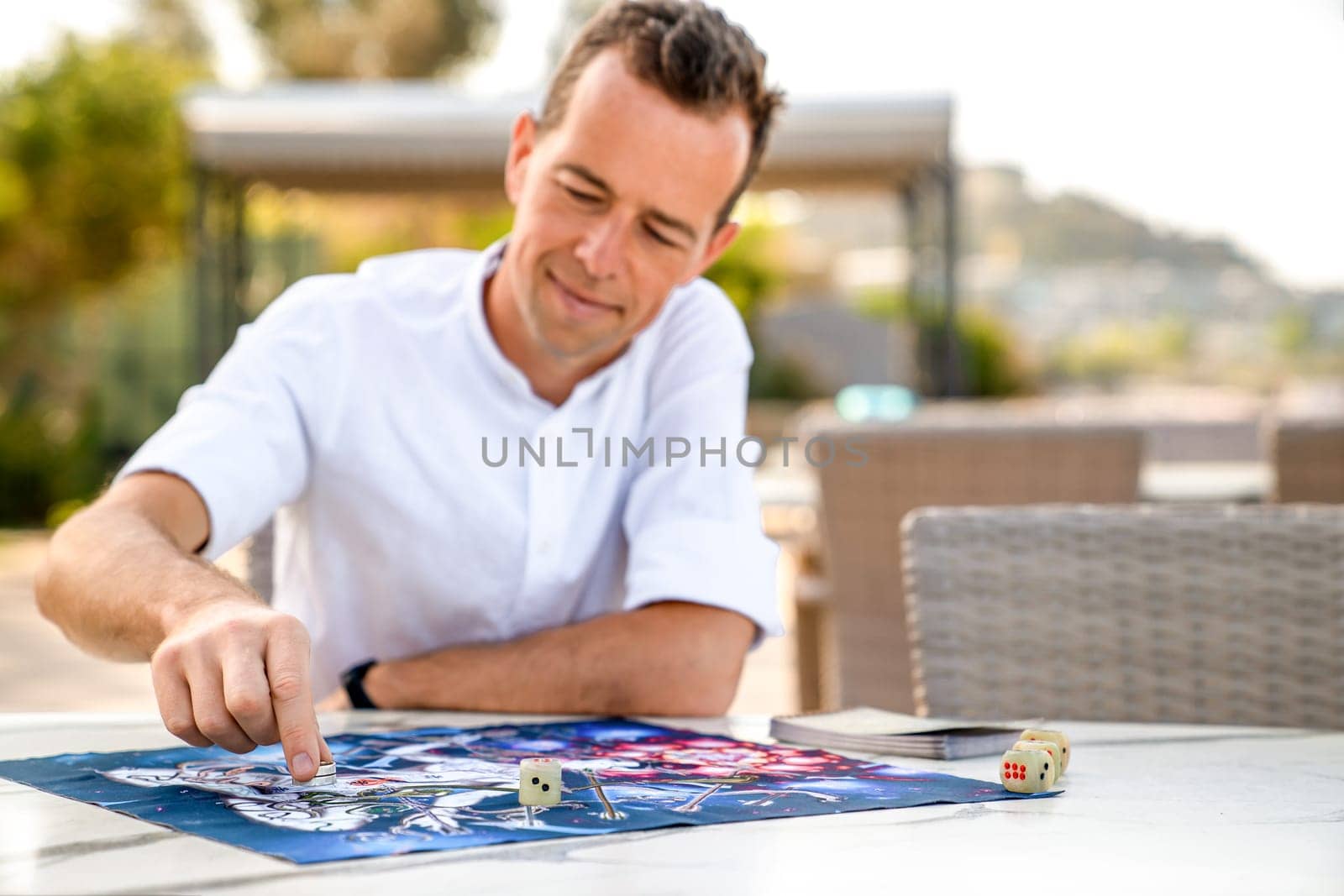 Portrait of Man Playing Ancient Indian Board Game 'Leela', Making Move with Game Piece, Seated at Outdoor Table, Turkey, Alanya - April 14, 2024. by Laguna781