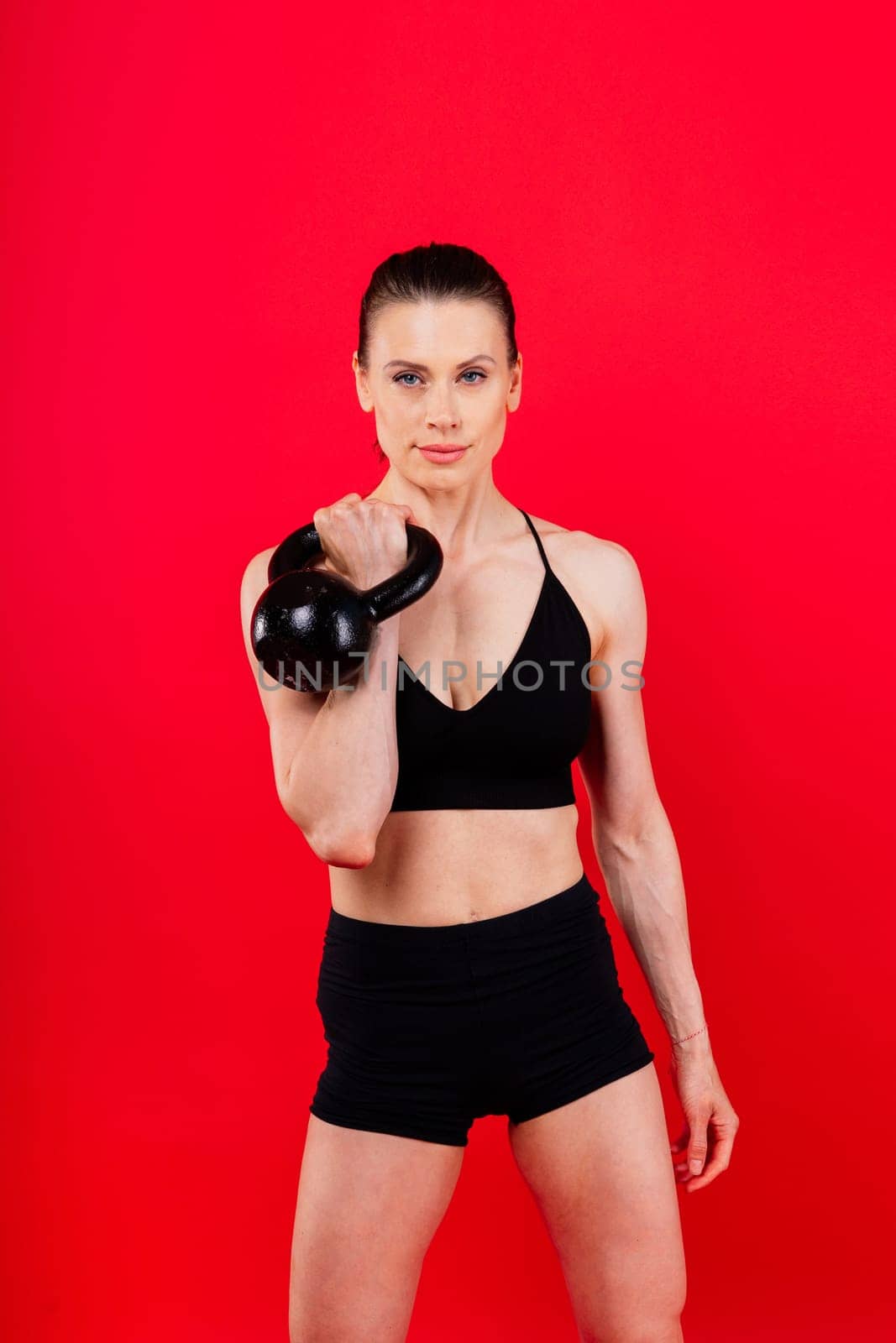 Slim, woman and kettlebell in workout for fitness, exercise and wellness with weight in a studio.