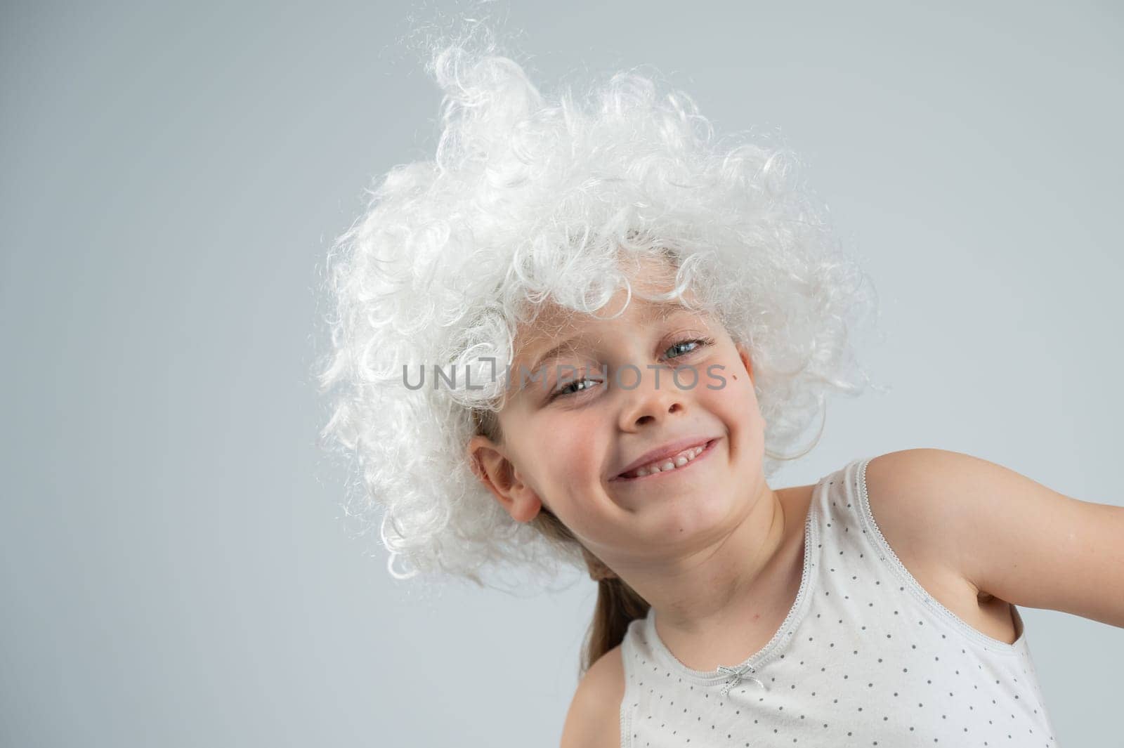 Portrait of a little Caucasian girl wearing a white curly wig on a white background