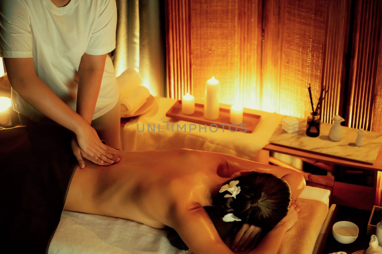 Caucasian woman customer enjoying relaxing anti-stress spa massage and pampering with beauty skin recreation leisure in warm candle lighting ambient salon spa at luxury resort or hotel. Quiescent