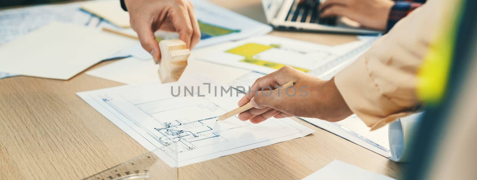 Skilled architect team using architectural equipment during colleague discussion about building design at meeting table with blueprint scatter around. Closeup. Focus on hand. Delineation.
