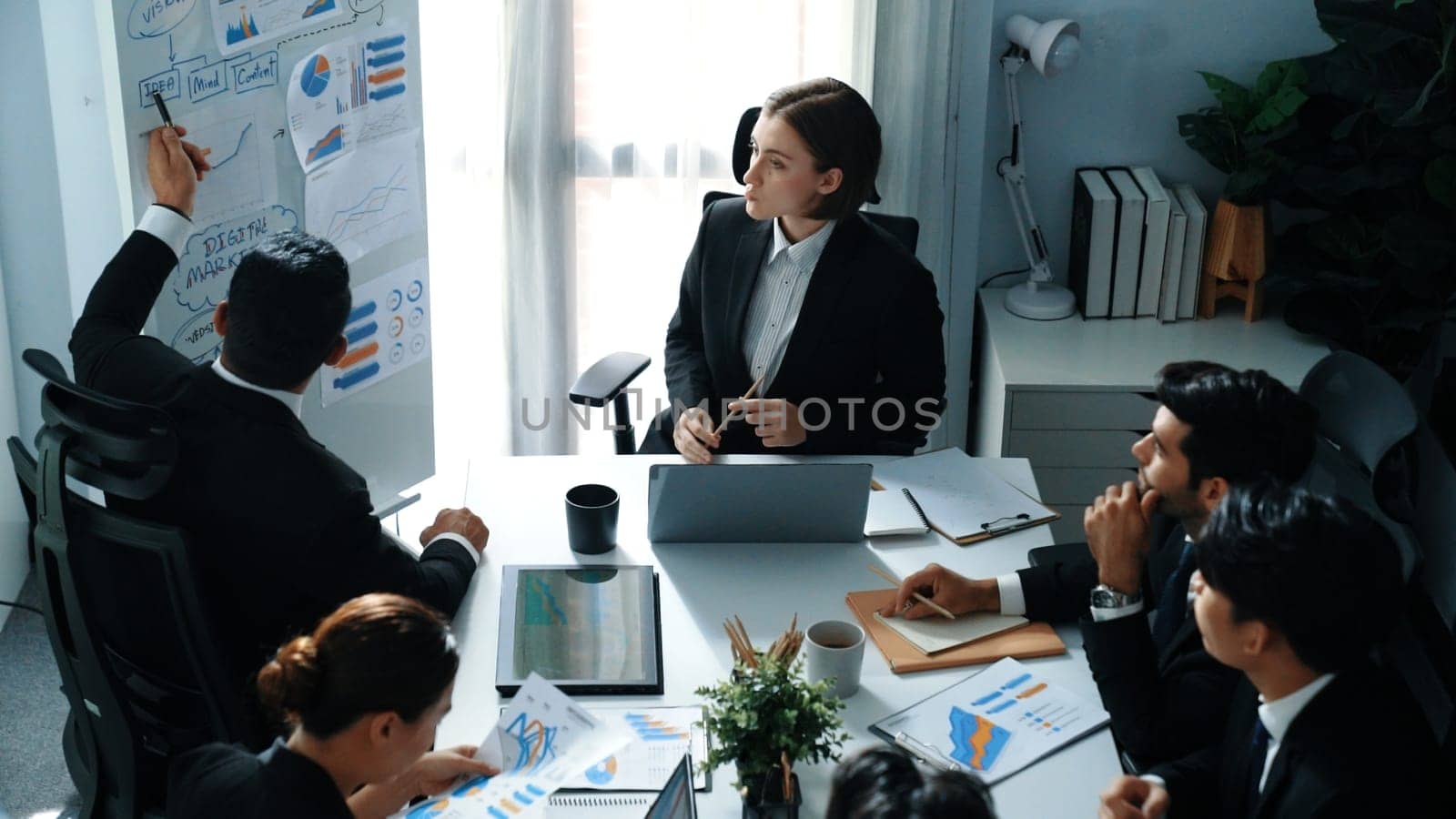 Top view of professional businesswoman pointing mind map and investment chart at whiteboard while looking at financial statistic graph. Marketing team working together to brainstorm idea. Directorate.