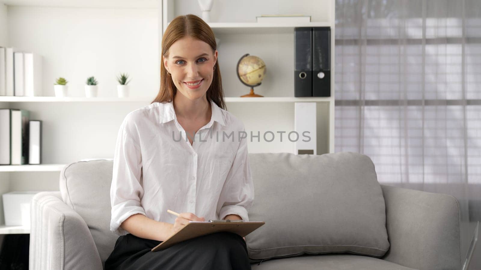 Friendly psychologist woman in clinic office professional portrait with smile and holding clipboard for patient to visit psychologist. The experienced and prim confident psychologist