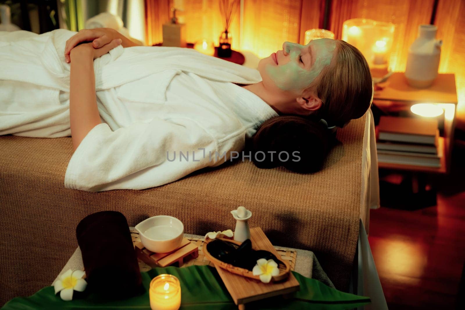 Serene ambiance of spa salon, woman customer indulges in rejuvenating with luxurious face cream massage with warm lighting candle. Facial skin treatment and beauty care concept. Quiescent