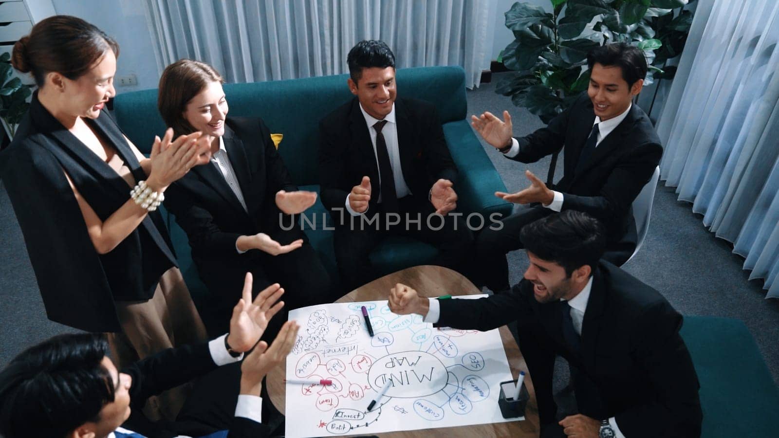 Top view of business people clapping hands to celebrate successful project while using mind map to brainstorm idea. Happy team clap handor applause successful plan while writing mind map. Directorate.