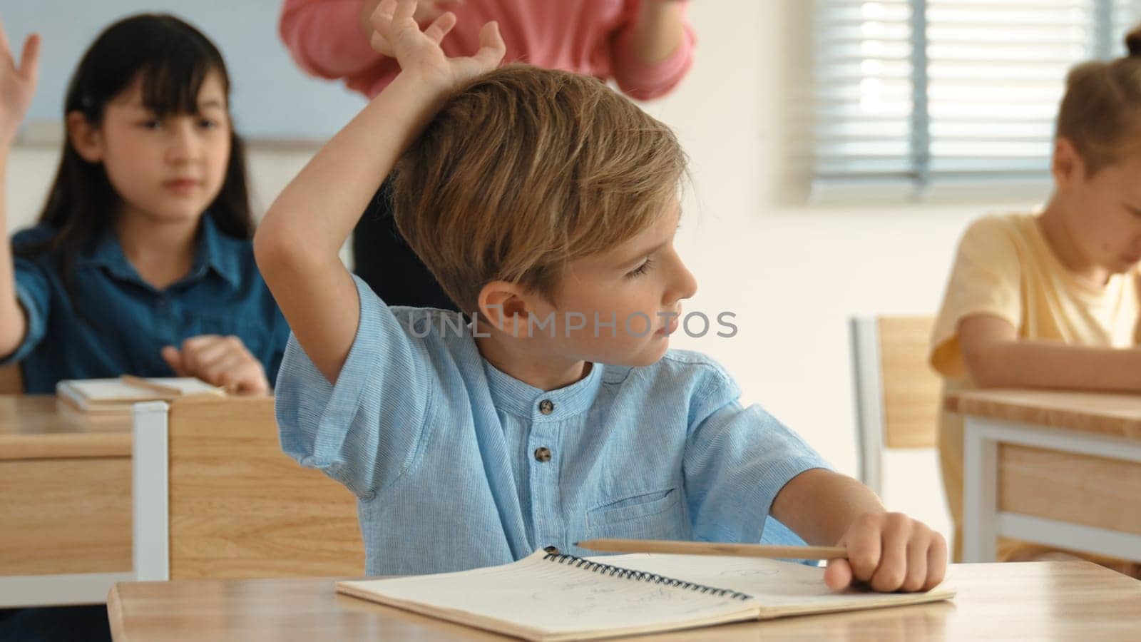 Caucasian boy looking at blackboard while diverse skilled student learning at school and taking a note. Smart child in casual cloth sitting in front of blackboard while children doing test. Pedagogy.