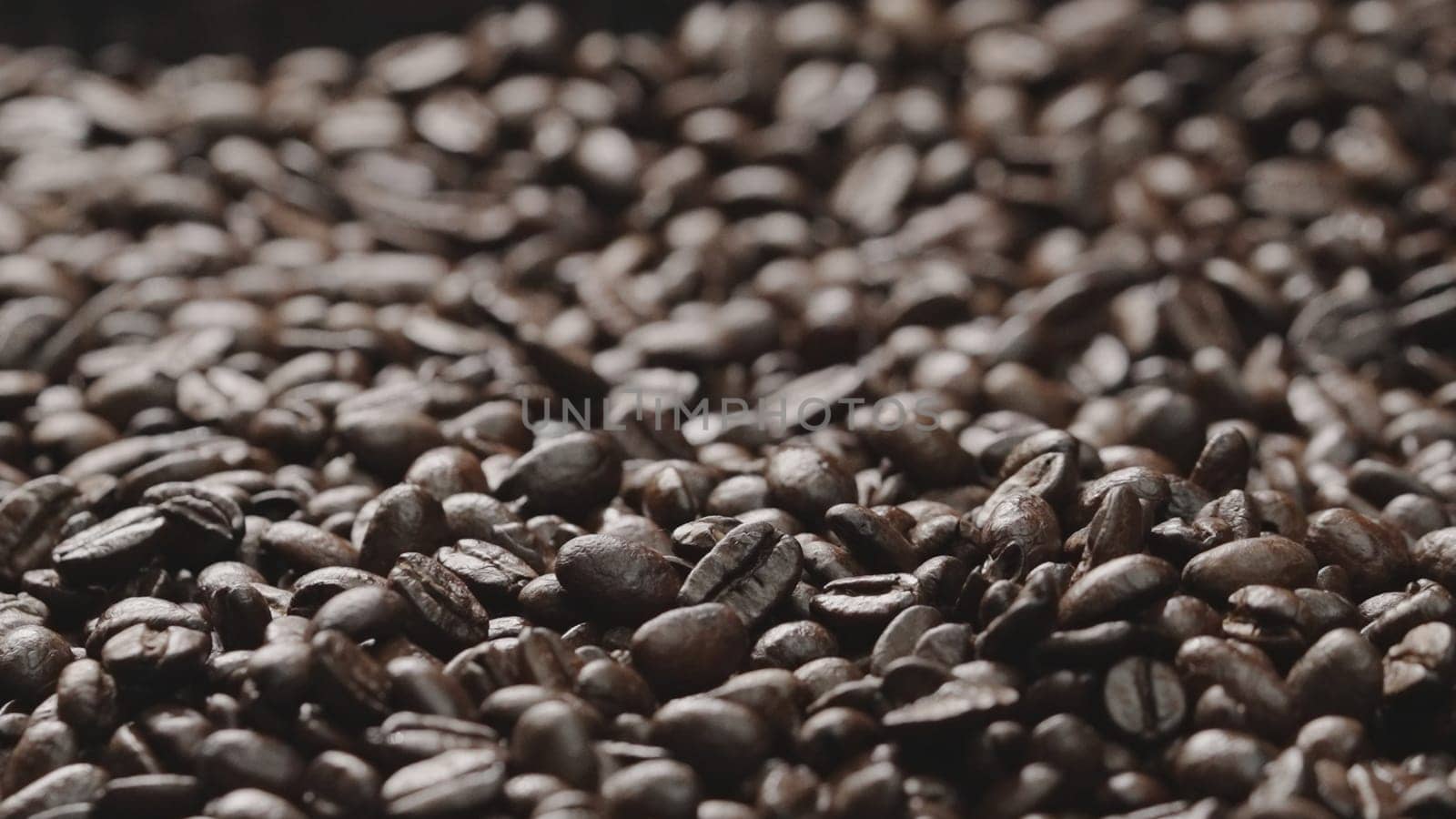Macro shot of super slow motion shot of fresh coffee bean placed with black background. Close up of piles of aromatic roasted coffee seed surrounded. Macrography. Beans scattering around. Comestible.