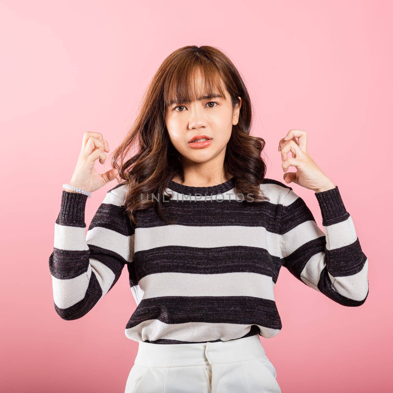 Asian happy portrait beautiful cute young woman standing angry and mad raising fist frustrated and furious while shouting with anger isolated, studio shot on pink background by Sorapop