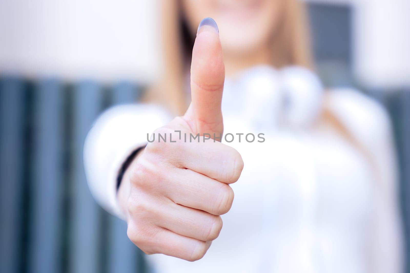 Unrecognizable young woman pointing thumb up looking smiling at camera by mariaphoto3