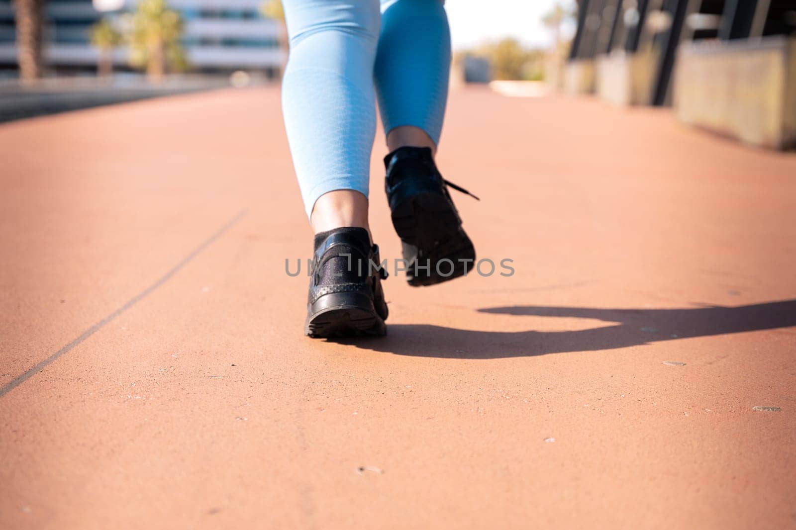 Feet of a sporty woman running through the streets of the city.