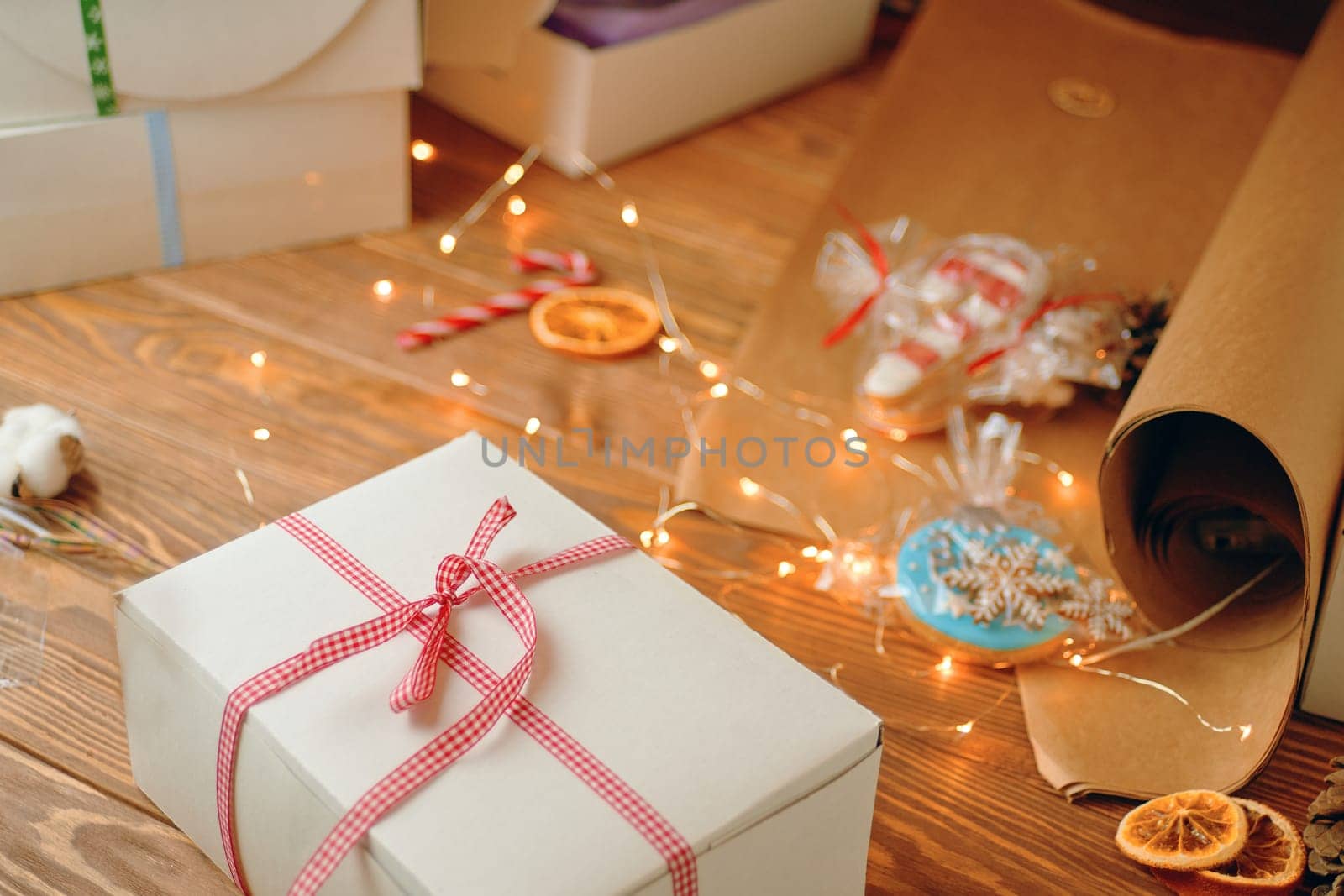 Christmas composition with present box. A Christmas gift box with a red ribbon stands on a wooden table.