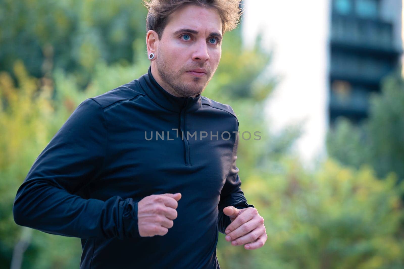 Young caucasian athlete with headphones training outdoors.