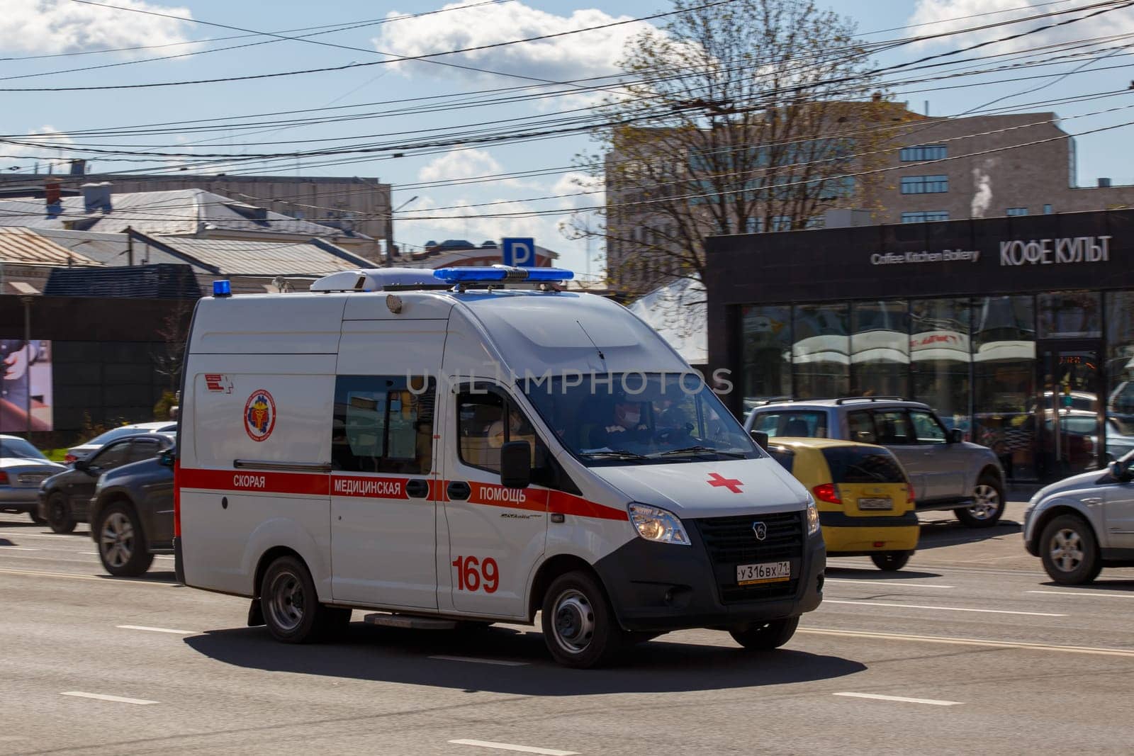 white ambulance minibus driving along city street at sunny day in Tula, Russia - June 7, 2021