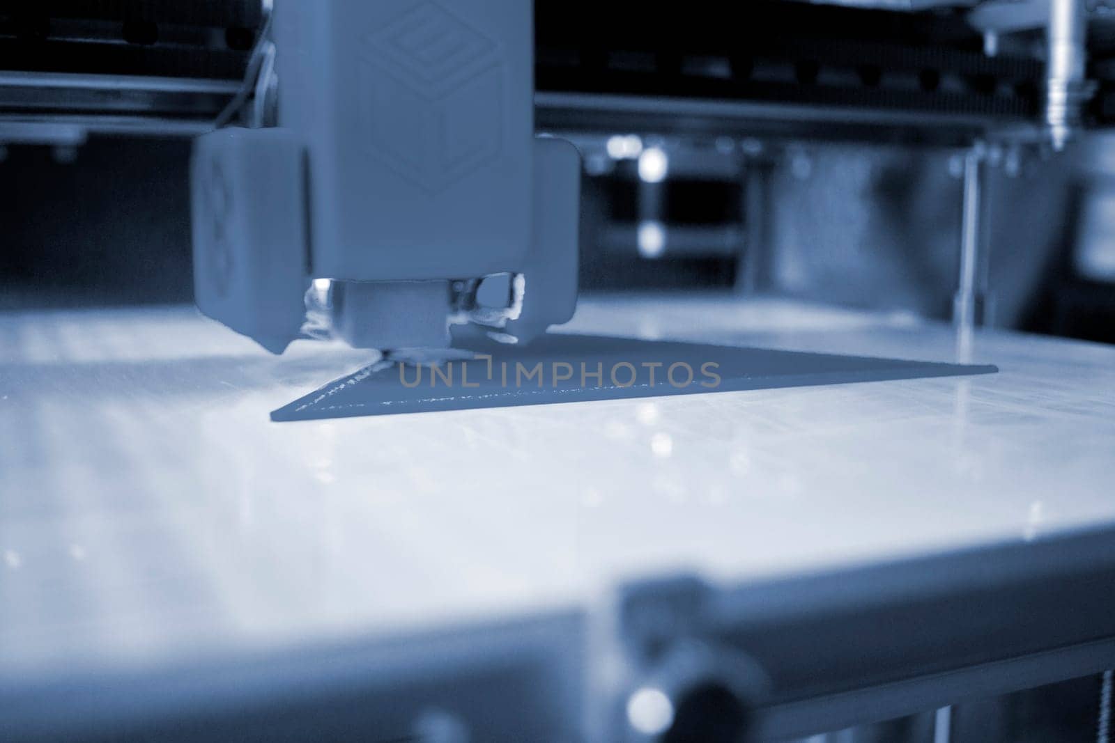 3D printer close up. A working 3D printer in process of printing object from molten plastic. 3D printer creating model by flowing liquid plastic from an extruder of printer. 3D printing technology