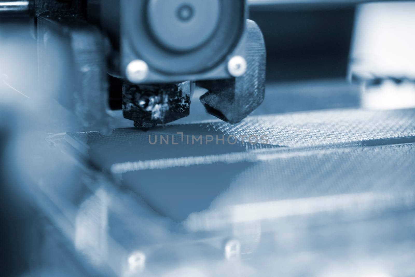 3D printer close up. A working 3D printer in process of printing object from molten plastic. 3D printer creating model by flowing liquid plastic from an extruder of printer. 3D printing technology