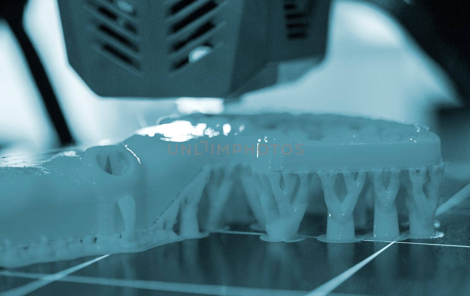 3D printer close up. A working 3D printer in process of printing object from molten plastic. 3D printer creating model by flowing liquid plastic from an extruder of printer. 3D printing technology