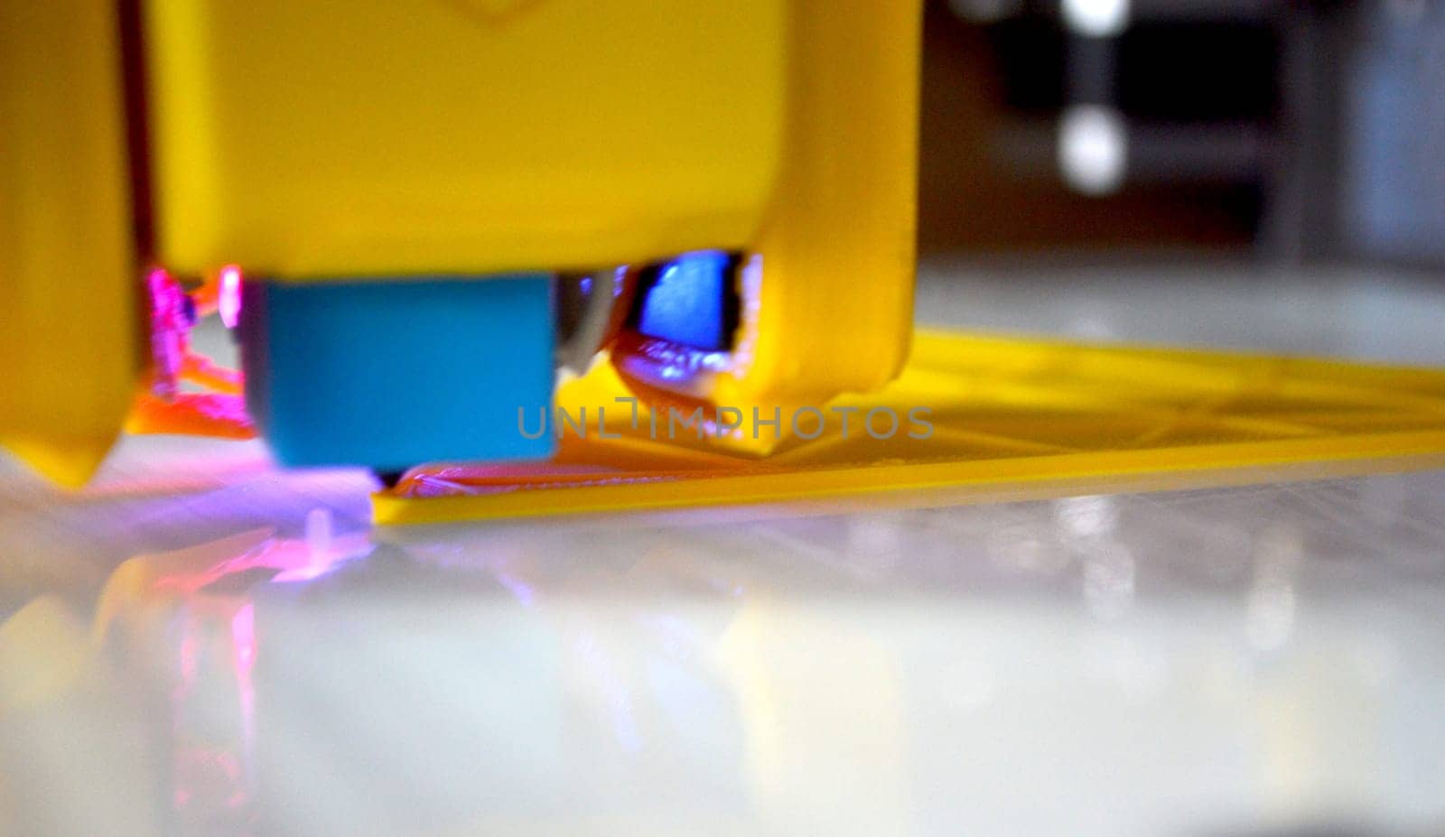 3D printer close up. A working 3D printer in process of printing object from molten plastic. 3D printer creating model by flowing liquid plastic from an extruder of printer. 3D printing technology