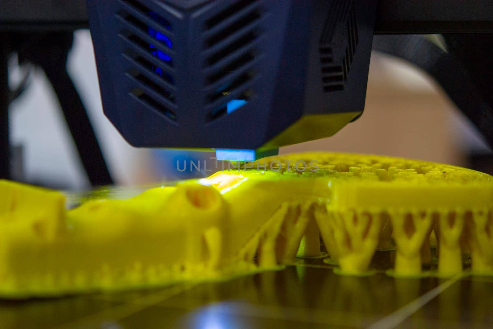 3D printer close up. A working 3D printer in process of printing object from molten plastic. 3D printer creating model by flowing liquid plastic from an extruder of printer. 3D printing technology