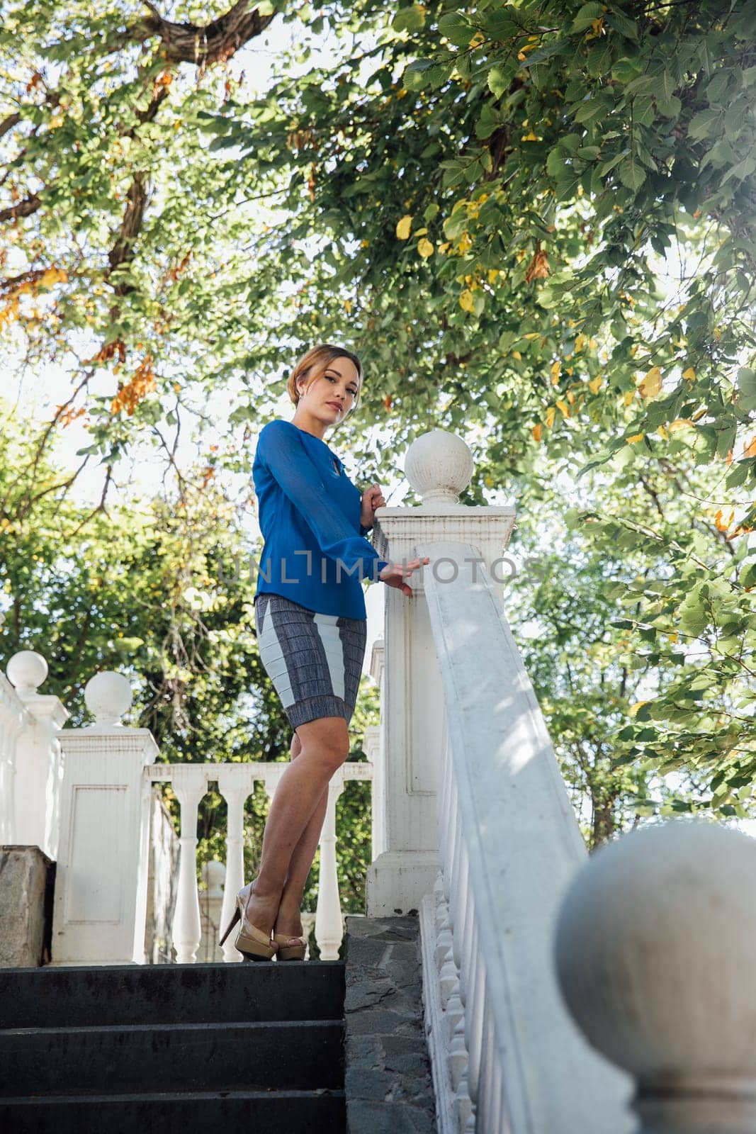 woman in blue clothes stands at the railing near the stairs on the street walking