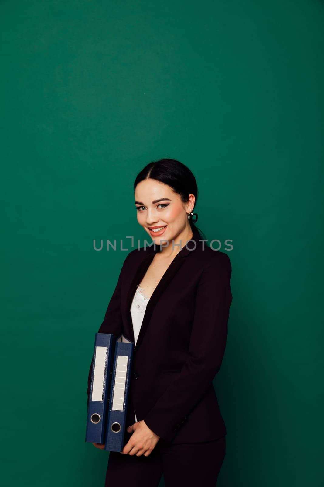 business woman in a black suit stands with folders in an office space