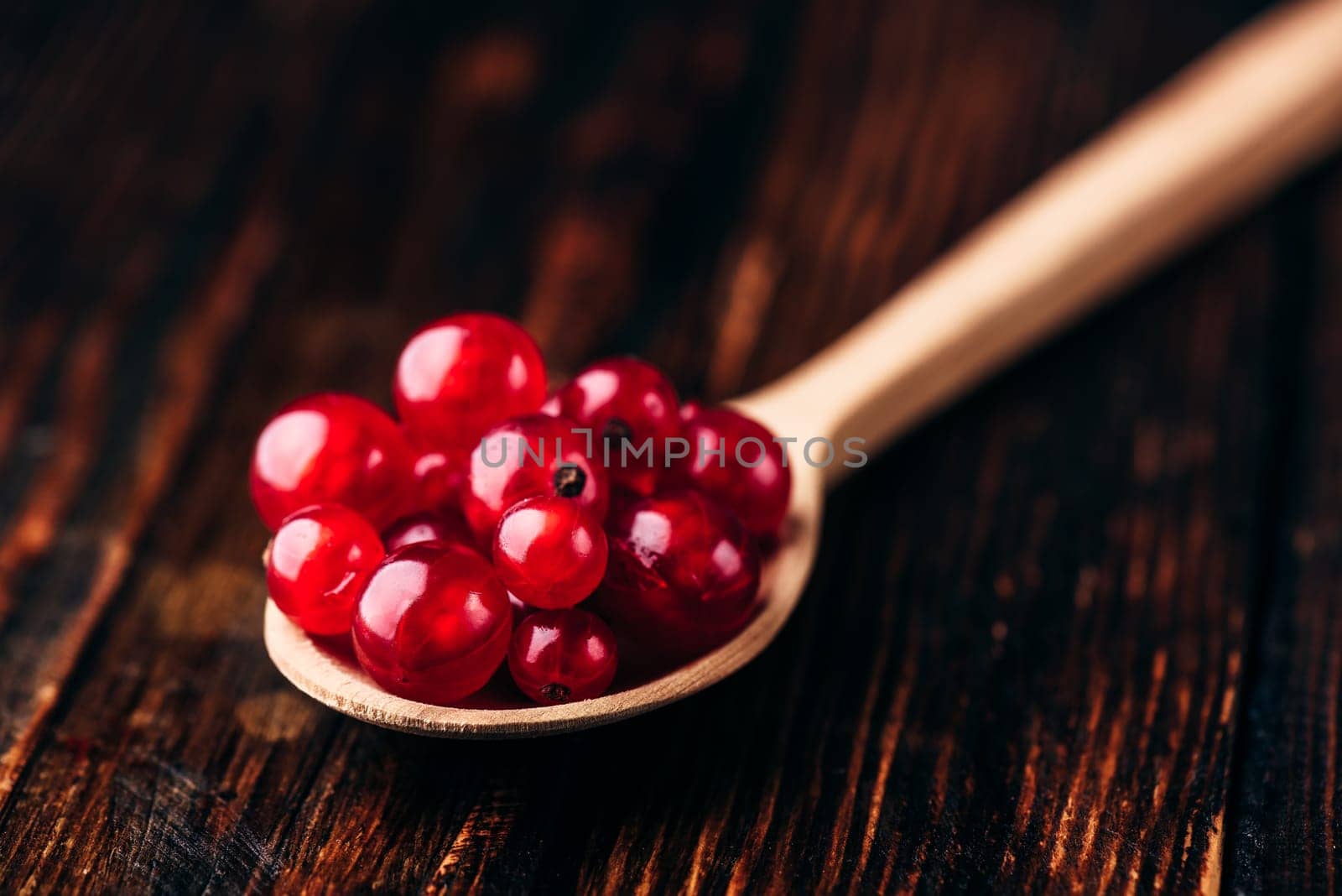 Spoonful of red currant over the dark wooden surface