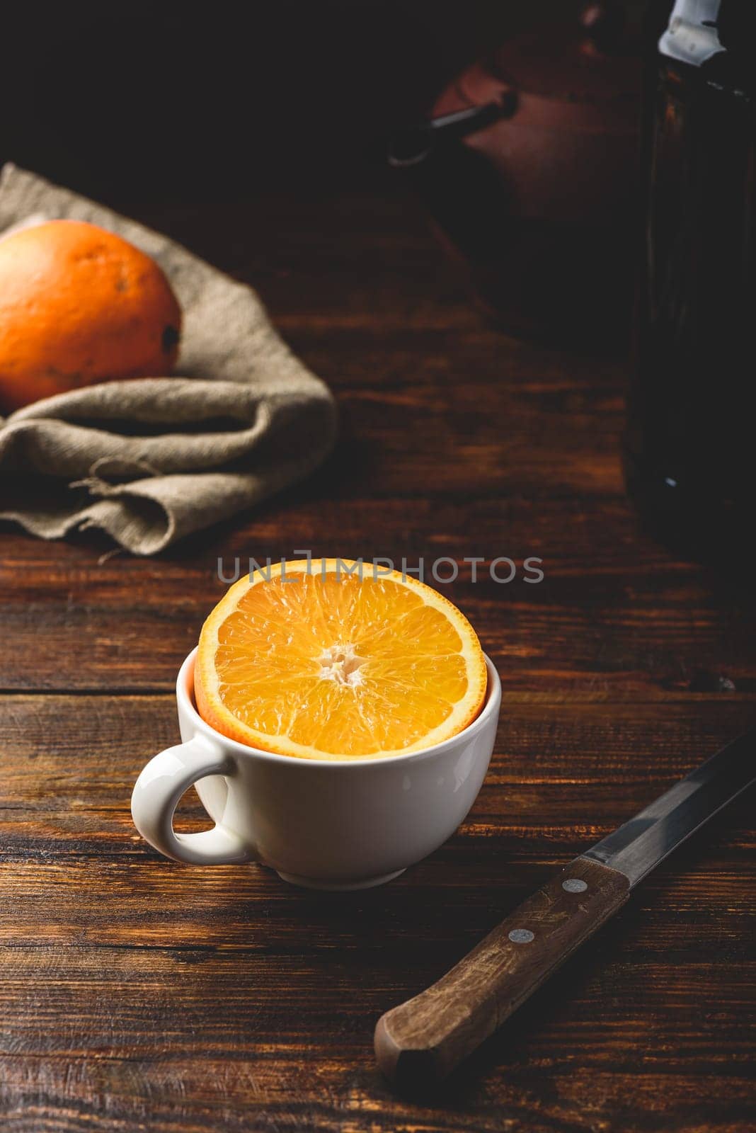 Half of orange in a white cup over rustic table