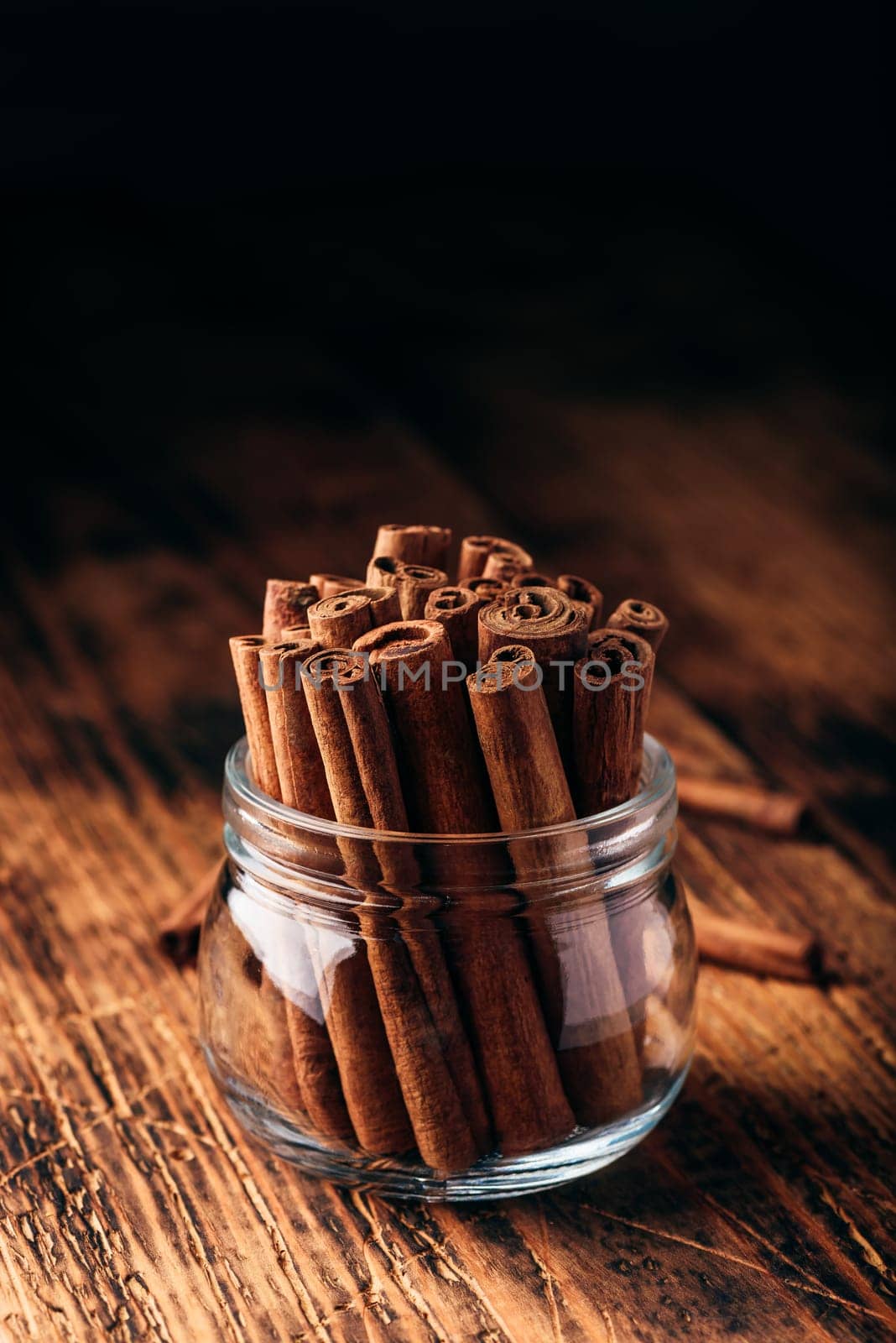 Cinnamon sticks in a glass jar over rustic wooden surface