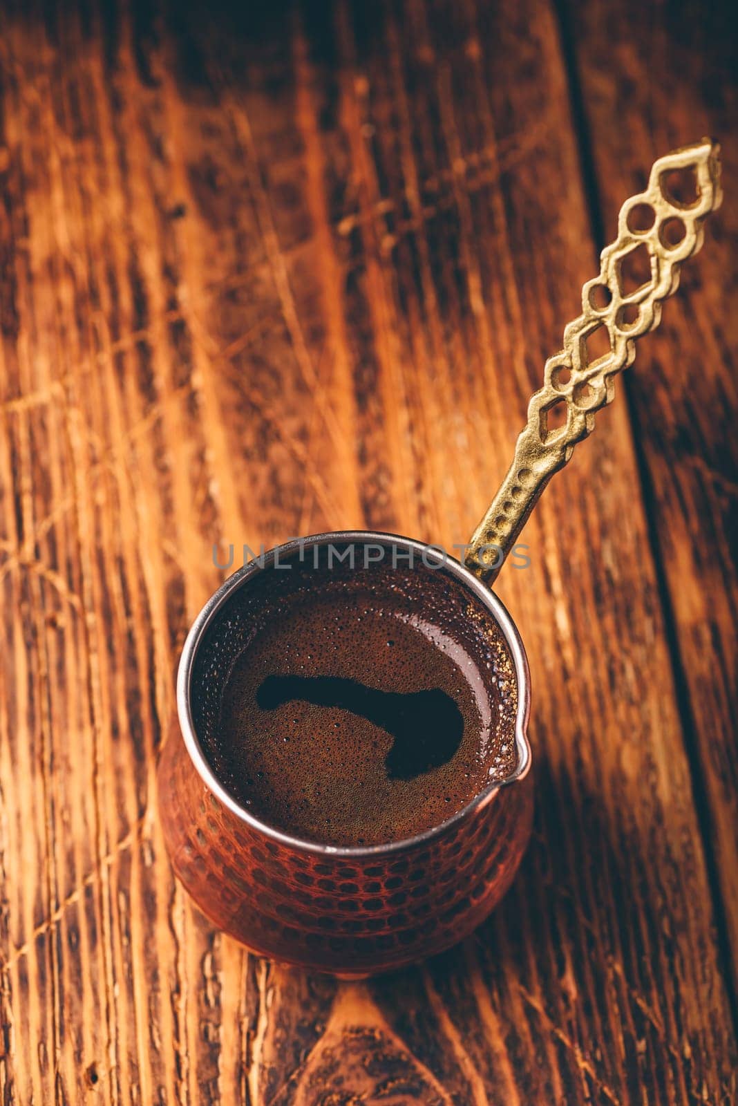 Turkish coffee. Brewed coffee in copper cezve on wooden surface