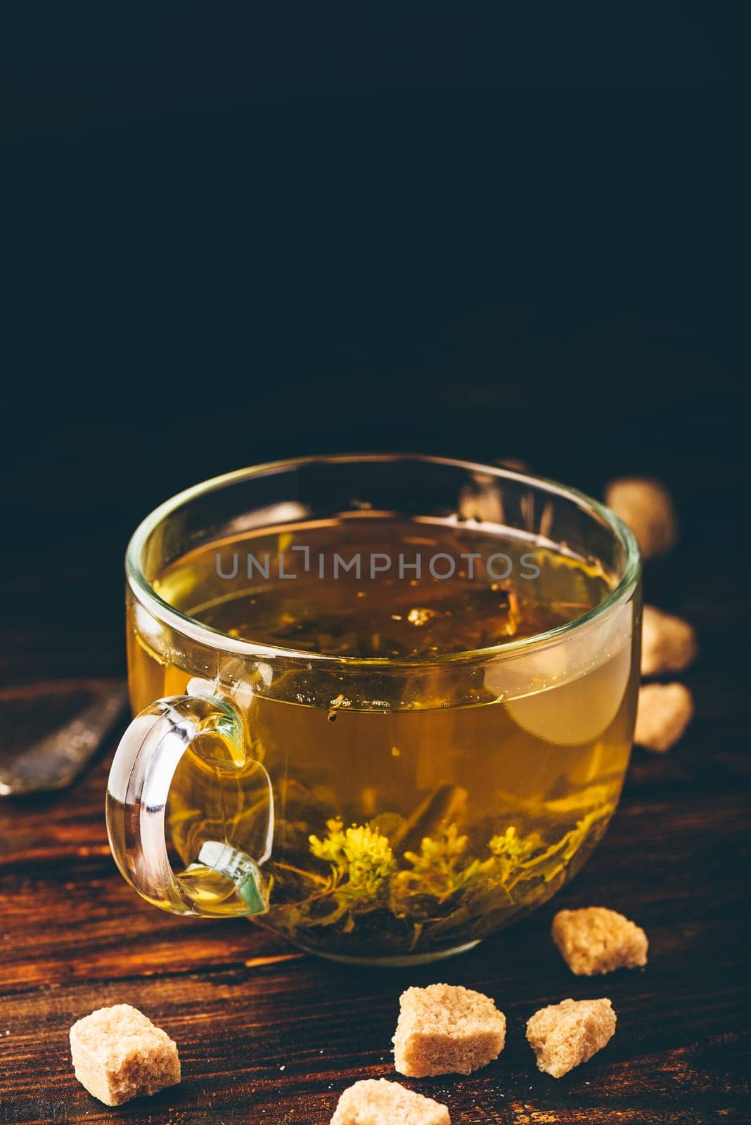 Cup of herbal tea with refined sugar on a wooden background