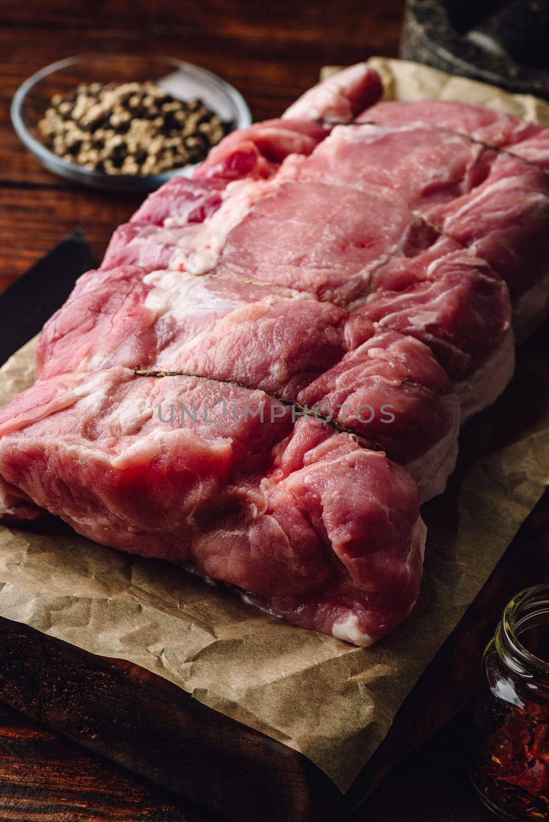 Raw pork loin joint on cutting board with different spices
