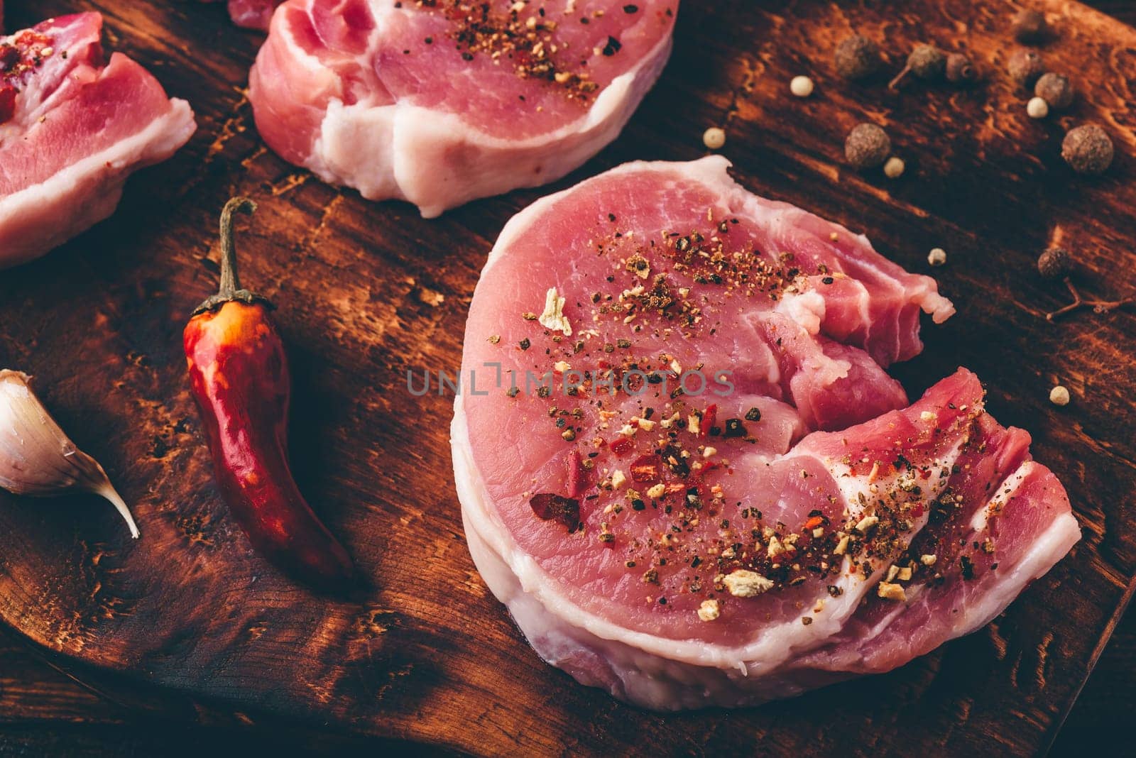 Pork loin steak with different spices on chopping board