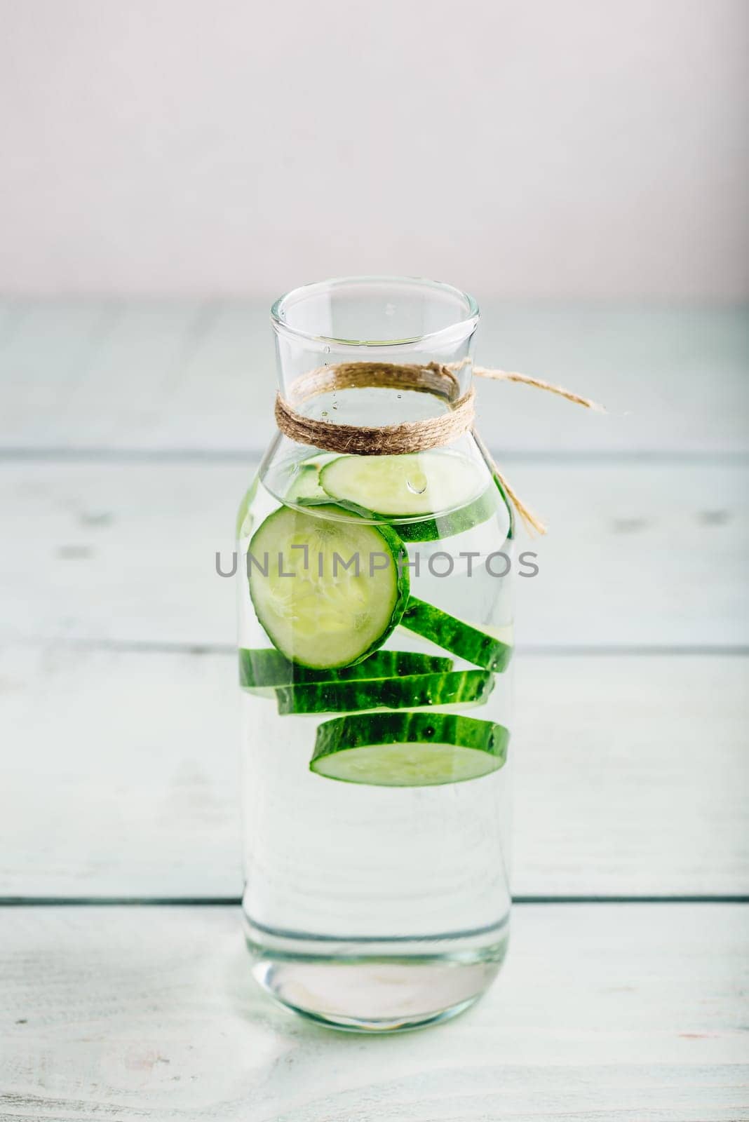 Infused water with sliced cucumber in glass bottle