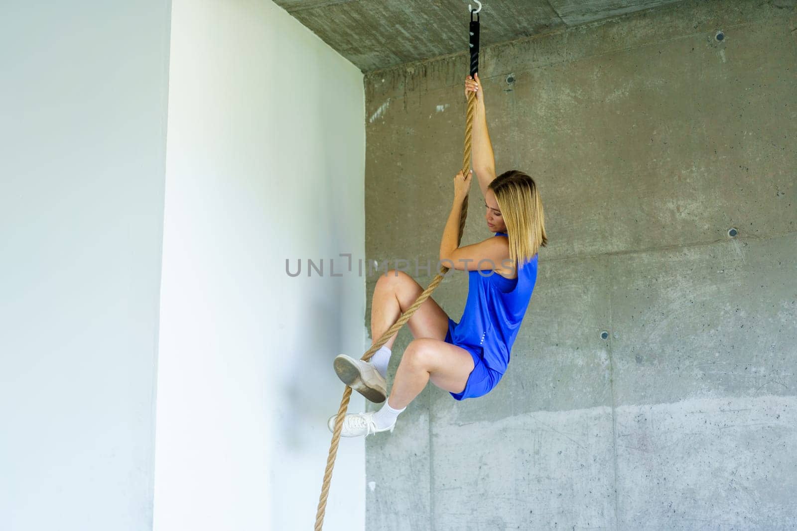 horizontal photo with copy space full length of a caucasian young woman cross training using rope in the gym