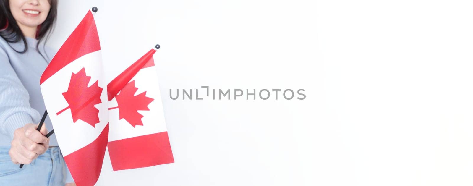 Unrecognized girl student in white blue shirt holding small Canadian flag over gray background, Canada day, holiday, vote, immigration, tax, copy space.