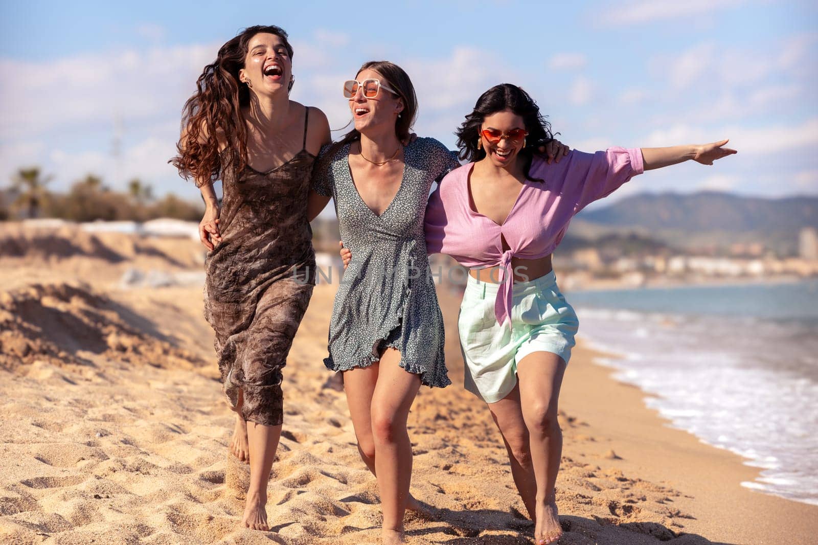 Cheerful multiethnic friends with sunglasses happy on vacation on the beach, looking at the camera.