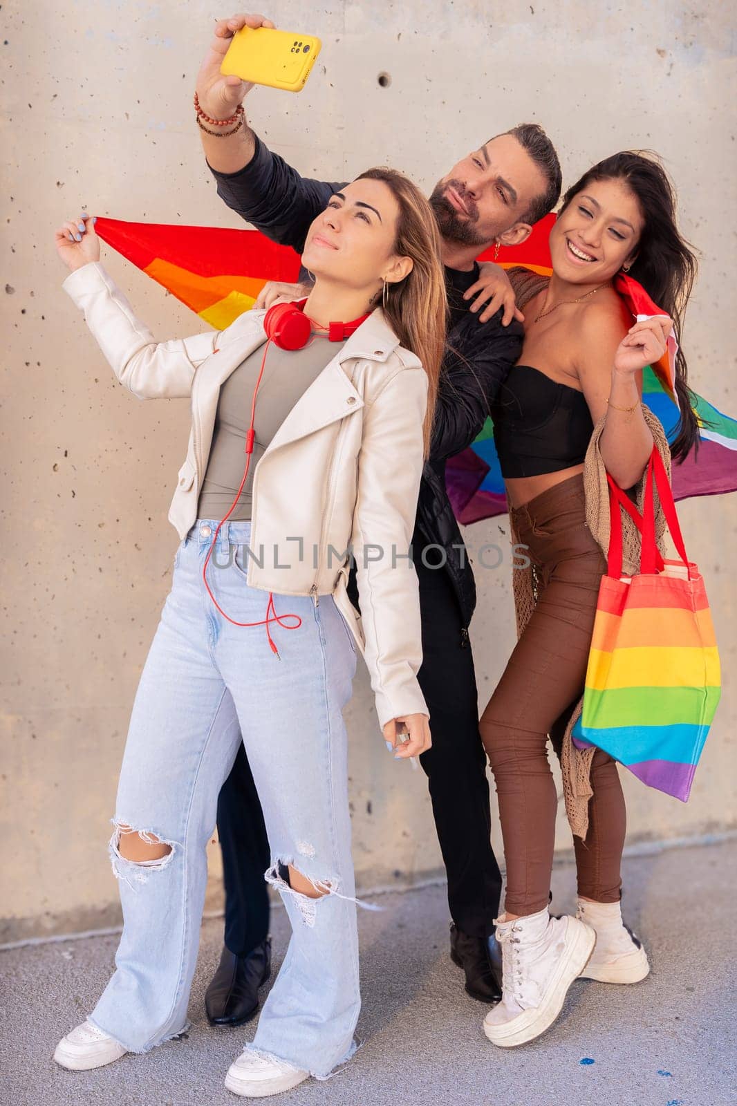 Happy multiethnic group of young gay friends take a selfie together on campus. Multiracial students meeting in the city, concepts of youth, people's lifestyle, diversity and pride.