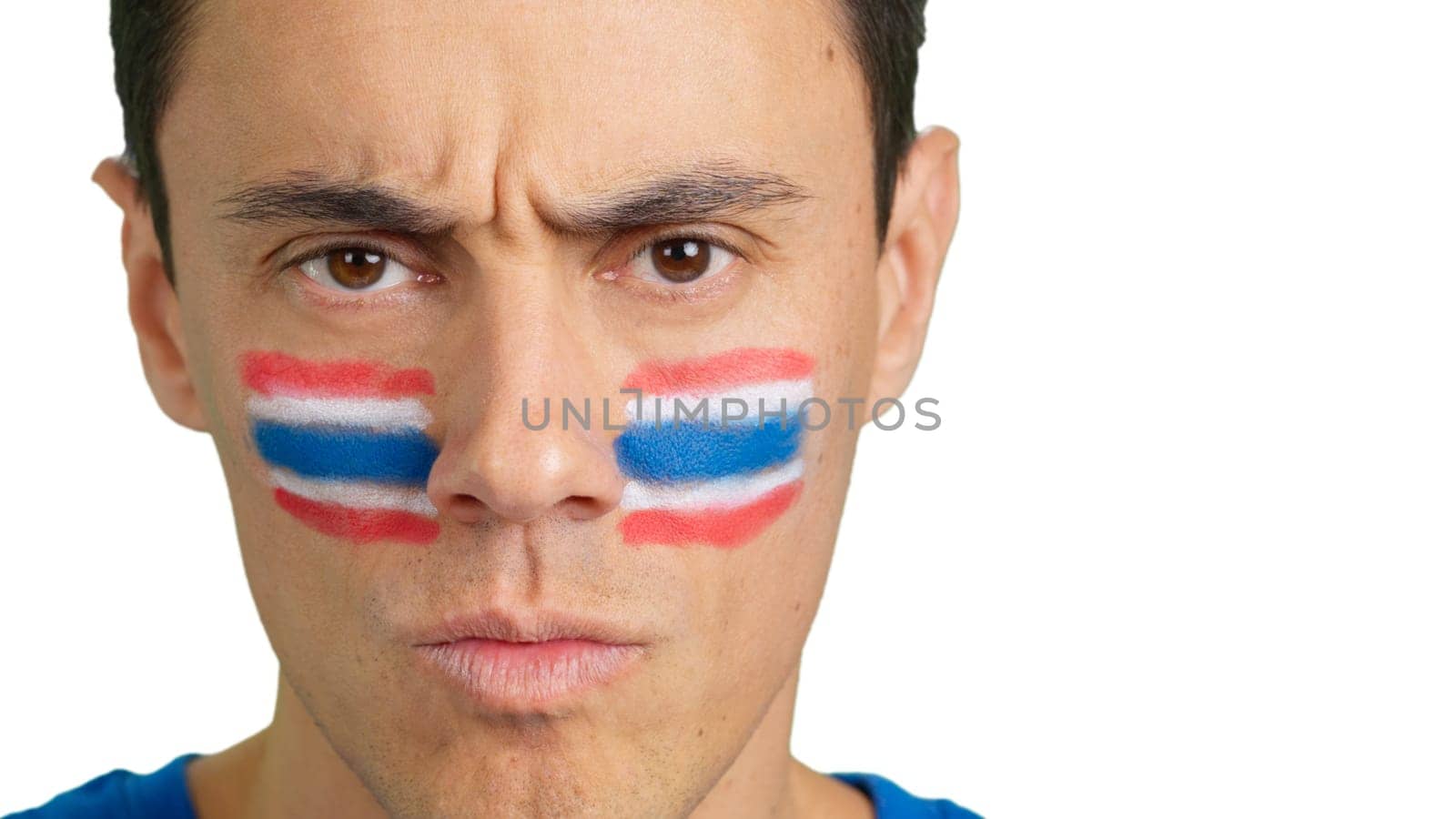 Close up of a serious man with a thai flag painted on the face looking at camera