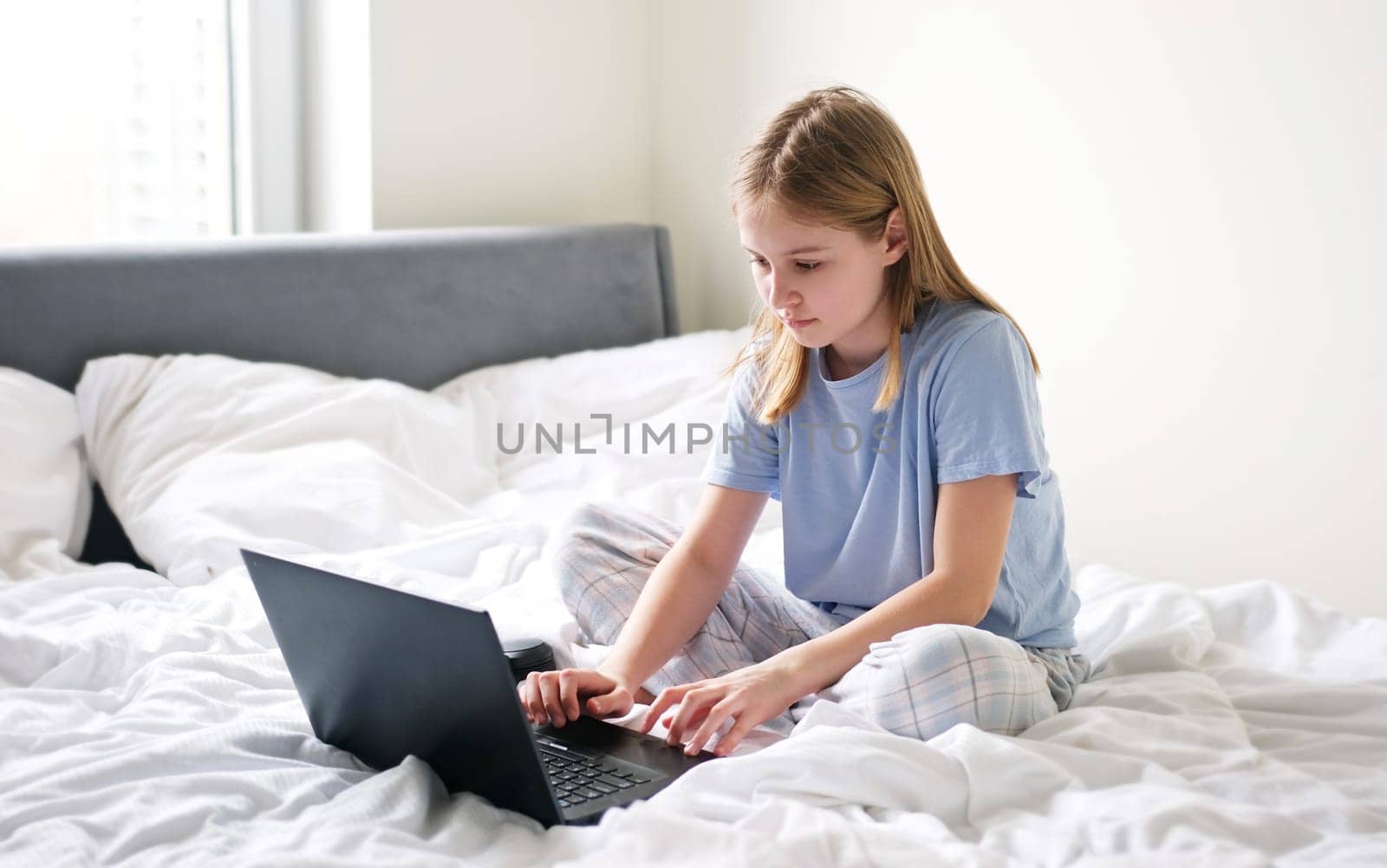 Cute Preschool Girl Surfing The Internet Early In The Morning On The Weekend While In Bed
