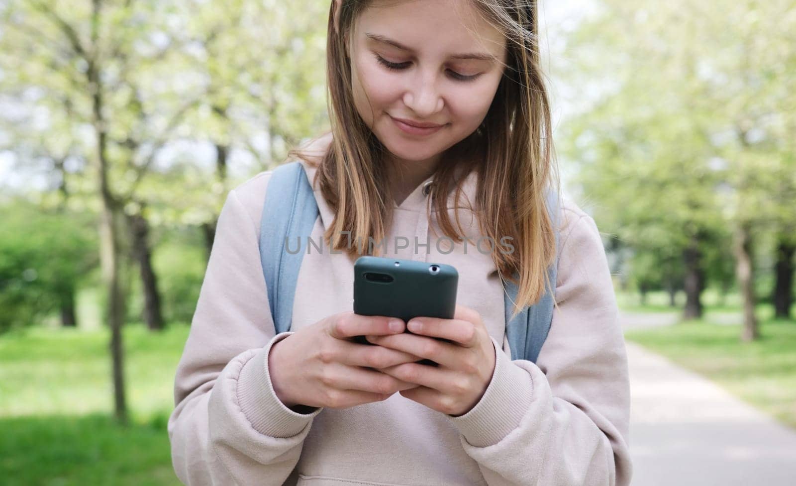Adorable Small Girl Using A Smartphone In The Park