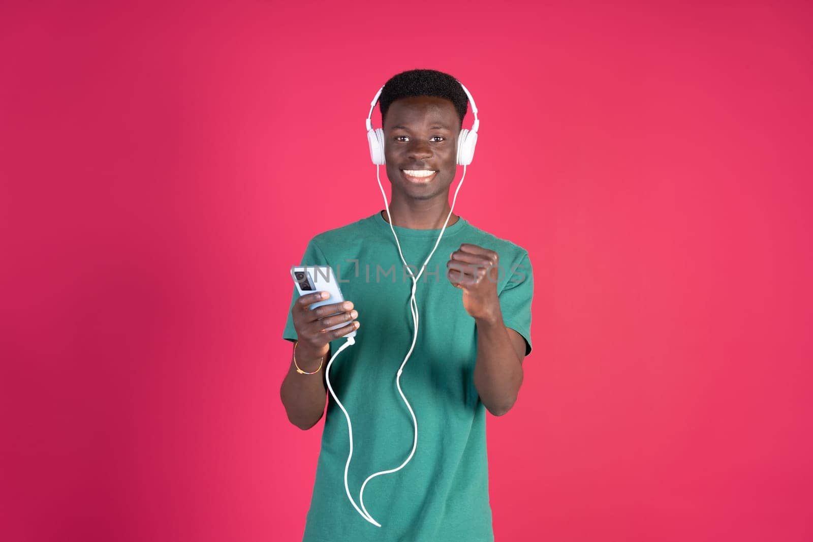 A young man is wearing headphones and holding a cell phone by Ceballos