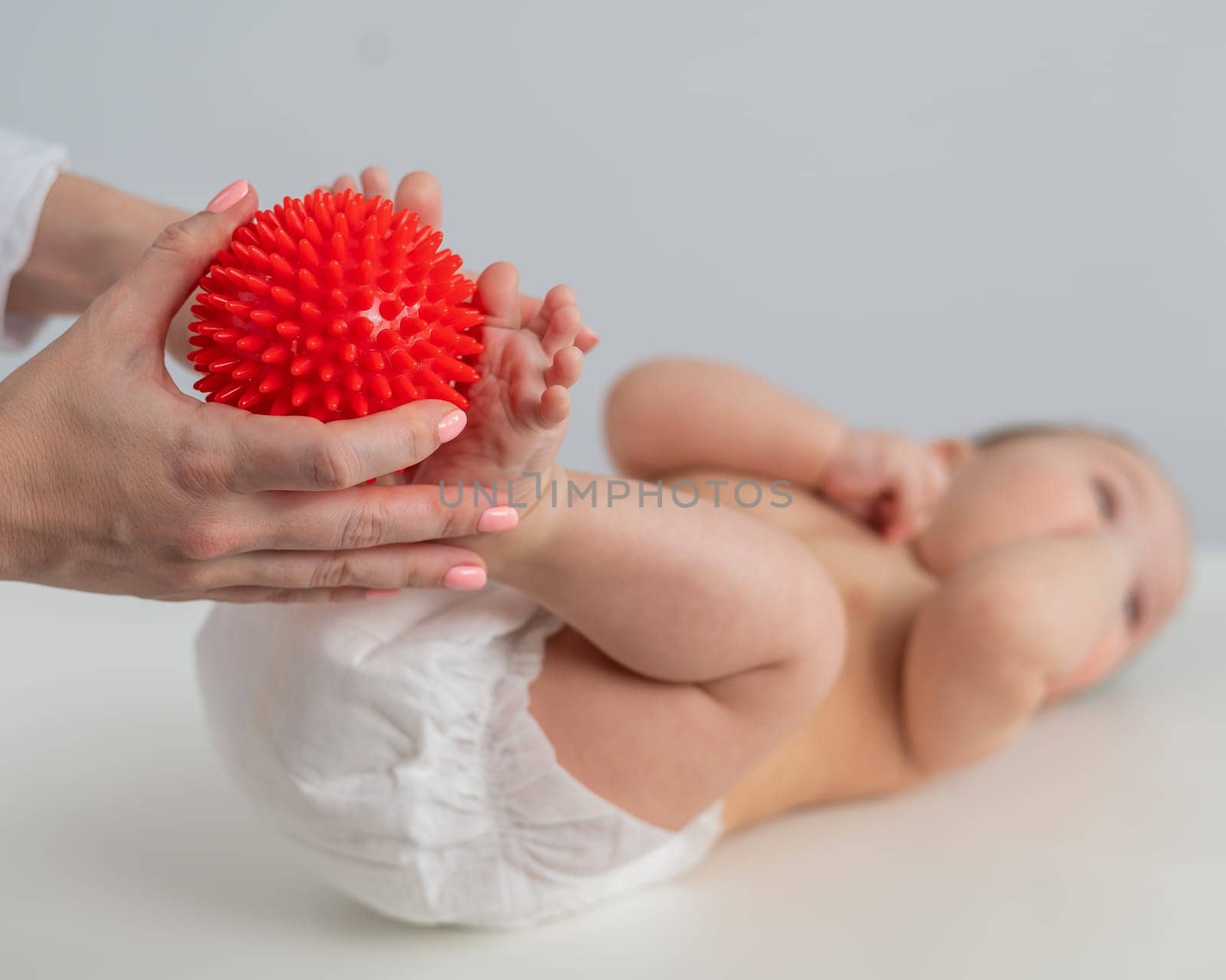 A doctor massages a baby's foot using a spiked ball