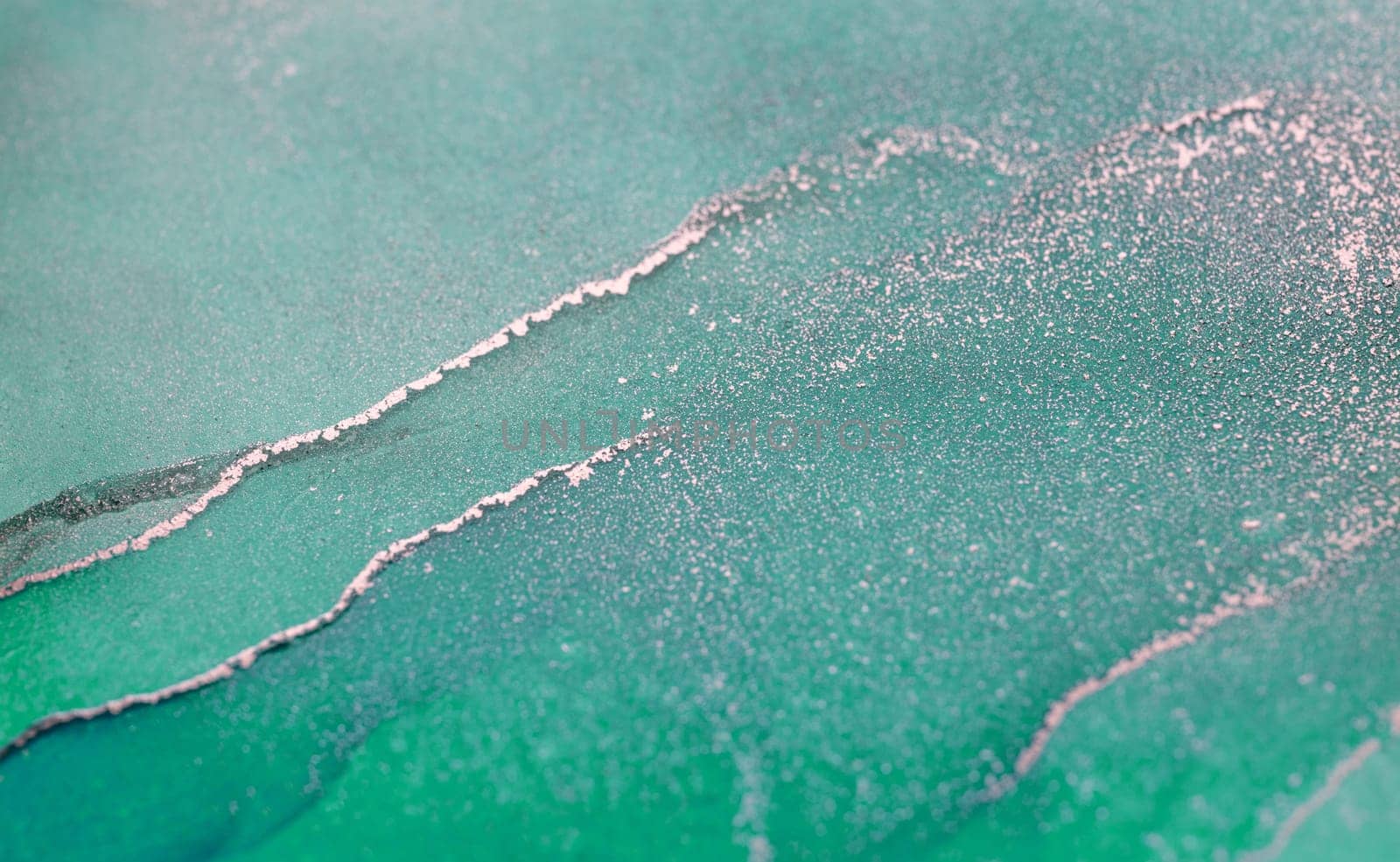 An abstract painting featuring flowing, swirling teal and silver ink. The artwork creates a sense of depth and movement, with light and dark areas intermingling.
