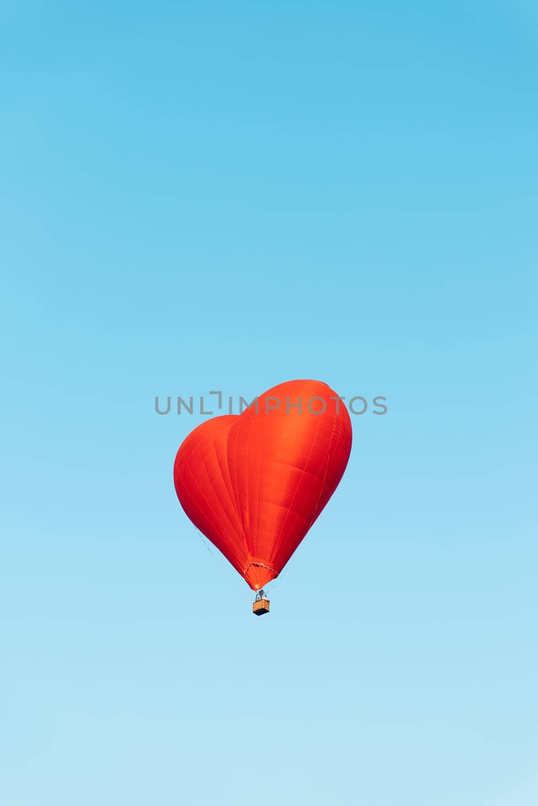 red heart shaped balloon soaring against a vibrant blue sky backdrop