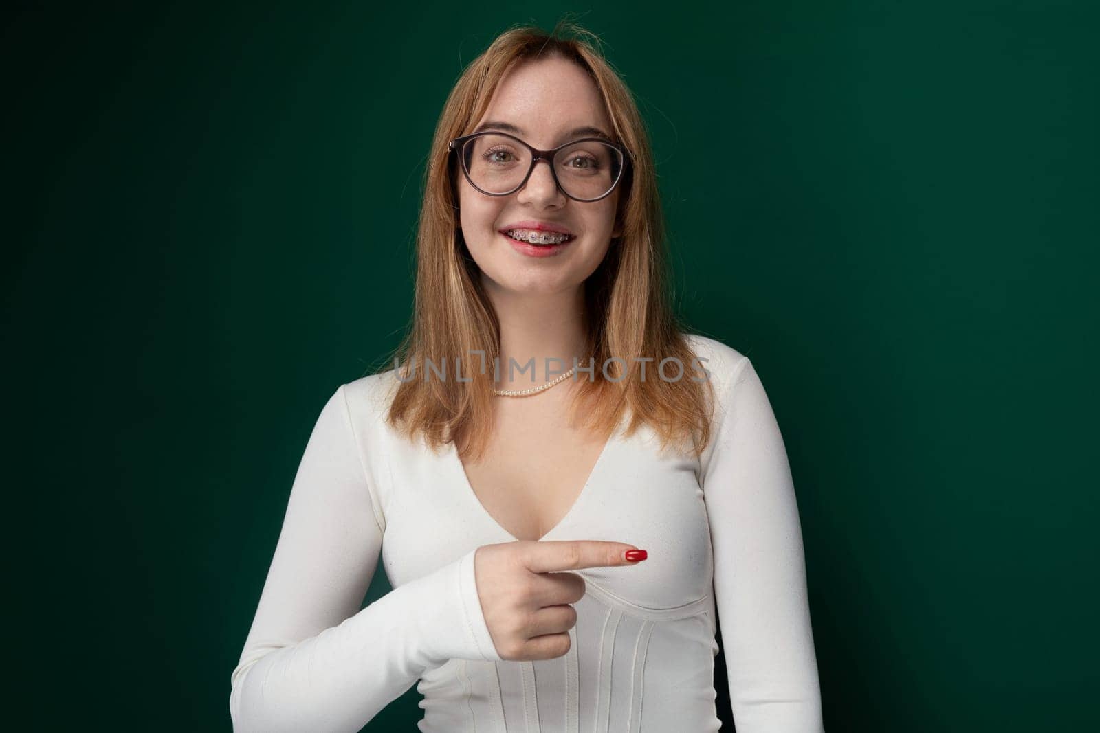 A woman with glasses pointing at an object in the distance. She is focused and appears to be directing attention towards a specific thing with her hand. The womans facial expression conveys determination and focus.