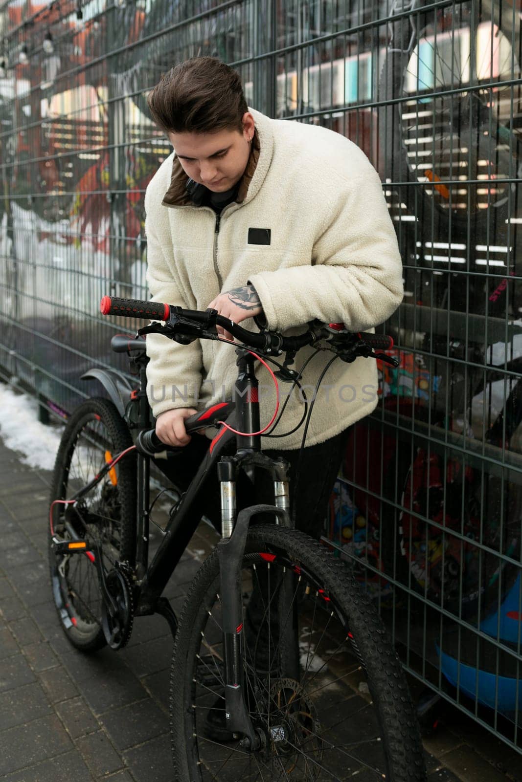 Young European man dressed in a winter jacket rides a bicycle.